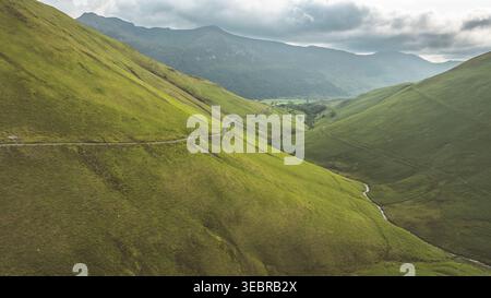 La fotografia cattura un paesaggio sereno con una strada che serpeggia attraverso colline verdeggianti, offrendo un senso di avventura Foto Stock