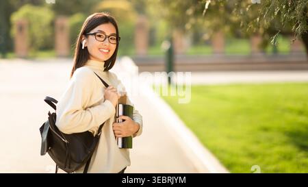 La giovane donna che porta una Thermos si trova in un Sunny Park con Green Grass Foto Stock