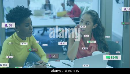 Parlare con due donne che indossano la parte superiore gialla, prendere appunti al tavolo dell'ufficio con la sovrapposizione sociale del laptop Foto Stock
