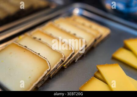 Fette di formaggio francese su vassoio nel display del mercato di Antibes, Francia Foto Stock
