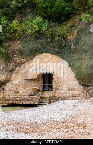 Porta di ingresso in pietra con barre di ferro sulla costa frastagliata di Monaco Foto Stock