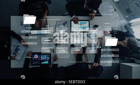 Un team aziendale eterogeneo si occupa della gestione collaborativa dei progetti, utilizzando dispositivi digitali per l'analisi dei dati e la pianificazione strategica in un ambiente moderno Foto Stock