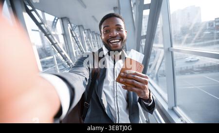 Happy Businessman Afro tenendo Selfie in aeroporto, tenendo il passaporto Foto Stock