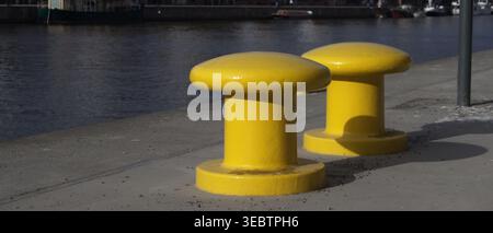 Paletti gialli di ormeggio sul lungomare presso il canale Hammarby a Stoccolma, Svezia Foto Stock