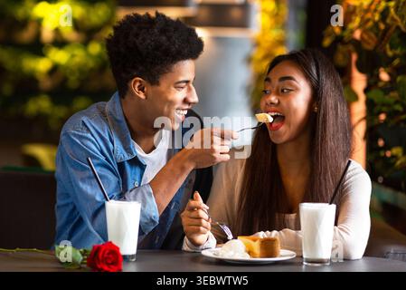 Coppia che gusta un dessert in un Cafe mentre condivide un momento di gioia in un ambiente intimo Foto Stock