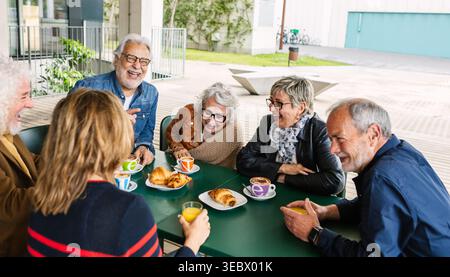Amici anziani felici che sorridono durante la colazione al bar Foto Stock