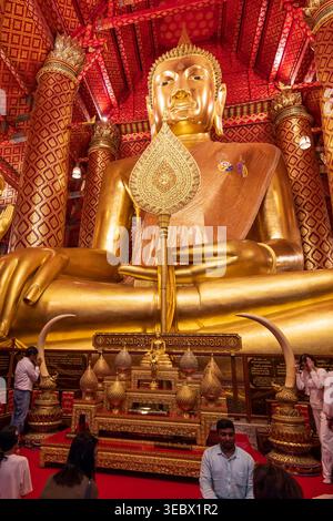 Phra Nakhon si Ayutthaya, Thailandia - 30 marzo 2025: Buddisti e devoti pregano di fronte a una statua dorata di Buddha seduto. Wat Phanan Choeng. Foto Stock