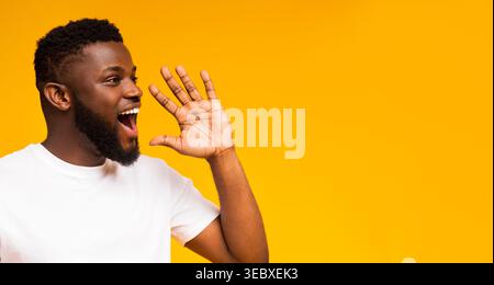 Giovane uomo che esprime gioia ed eccitazione su uno sfondo giallo brillante Foto Stock