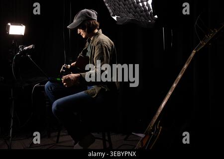Musicista in preparazione per la sessione di chitarra acustica Foto Stock