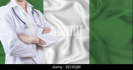 Medico con le braccia incrociate sulla bandiera della Nigeria. Concetto nigeriano di salute e assistenza. Dottoressa donna sulla bandiera della Nigeria Foto Stock