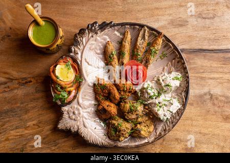 Una ricca varietà di kebab indiani, perfettamente grigliati e stagionati, disposti ad arte su un piatto decorativo. Accompagnato da rinfrescante menta Foto Stock