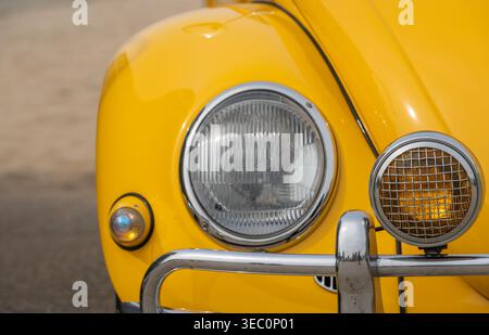 Katwijk aan Zee, Paesi Bassi, 11.04.2026, primo piano del faro di Maggiolino Volkswagen giallo, auto d'epoca d'epoca al vecchio spettacolo del timer Foto Stock
