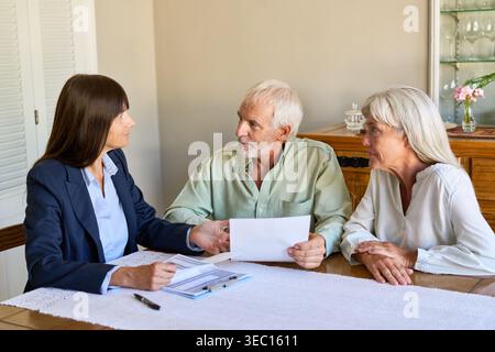 Una coppia di anziani si occupa di una discussione mirata sulla pianificazione pensionistica e la protezione finanziaria con un consulente professionale. Foto Stock