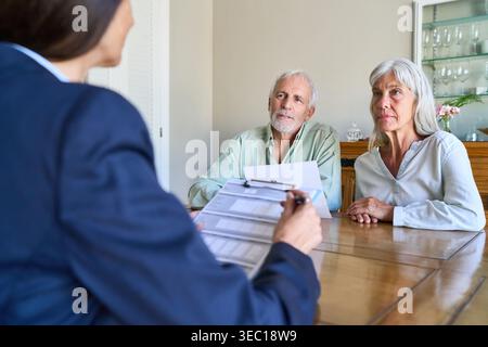 Una coppia di anziani si occupa di pianificazione pensionistica e di discussioni sulla protezione finanziaria con un consulente professionale a casa. Foto Stock