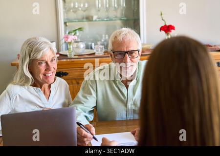 Pianificazione pensionistica e protezione finanziaria: Una coppia di anziani si impegna attivamente in una consultazione con un consulente finanziario, esaminando i documenti e di Foto Stock