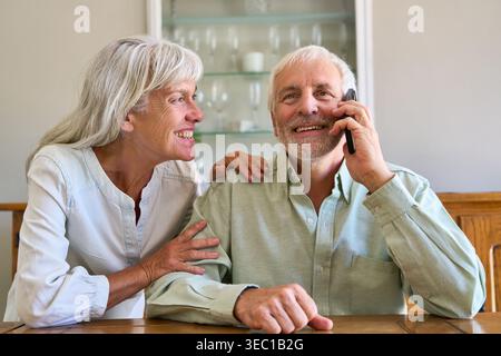 Una coppia di anziani è impegnata in una conversazione telefonica, probabilmente discutendo di pianificazione pensionistica e sicurezza finanziaria. Foto Stock