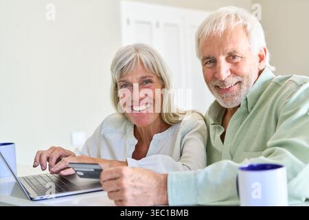 Una coppia di anziani felice si occupa di shopping online, dimostrando transazioni digitali sicure e una gestione finanziaria moderna. Foto Stock