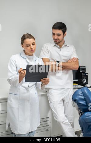Dentista professionista e infermiere che pianificano il trattamento del paziente in clinica Foto Stock