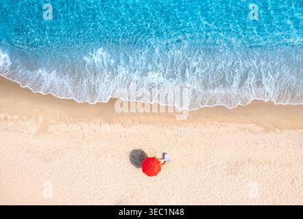 Veduta aerea dell'ombrellone rosso su una spiaggia bianca di sabbia bianca vuota, mare blu Foto Stock