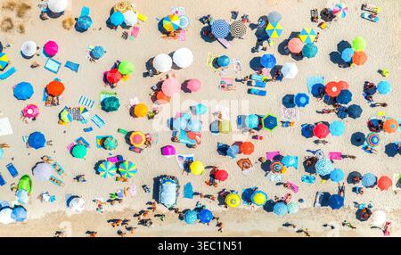 Vista aerea di ombrelloni colorati sulla spiaggia sabbiosa, persone rilassanti Foto Stock