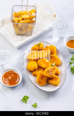 Pepite di pollo con patate fatte in casa e salse Foto Stock