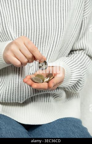 Donna che tiene e conta una pila di monete in euro nelle palme. Foto Stock