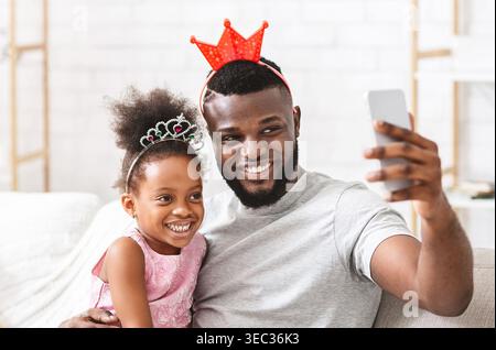 Padre e figlia si godono un momento festivo mentre fanno un selfie insieme a casa Foto Stock