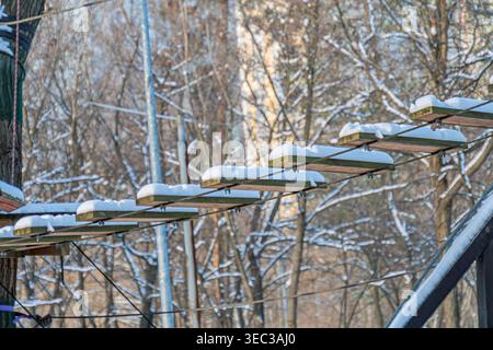 Ambiente innevato all'aperto con pista da montagna in metallo, alberi bianchi ricoperti di neve sullo sfondo, effetto di messa a fuoco morbida, illuminazione naturale ricoperta Foto Stock