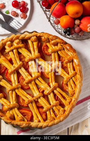 Torta di albicocche decorata con decorazioni a base di impasto e un cestino di metallo con frutta e frutti di bosco. Foto Stock