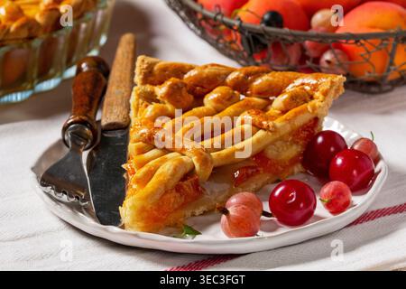 Torta di albicocche decorata con decorazioni a base di impasto e un cestino di metallo con frutta e frutti di bosco. Foto Stock