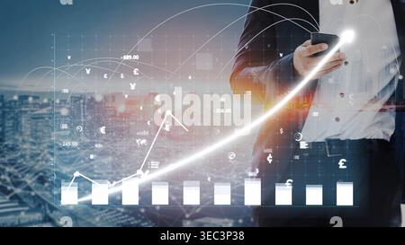 Un uomo d'affari esamina i grafici finanziari sul suo smartphone, evidenziando la crescita e l'analisi dei dati in un ambiente urbano vivace. La tecnologia moderna gioca un ruolo chiave Foto Stock