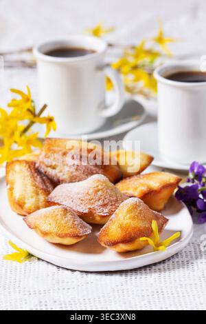 Madeleine Cakes con caffè e fiori di Forsythia, tavolo dei dessert primaverili Foto Stock