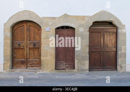 Vista frontale di 3 porte in legno di diverse forme e tipi di legno su un edificio residenziale esterno in Toscana, Italia Foto Stock