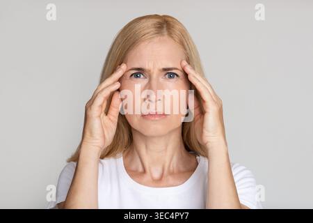 Sottolineato donna matura toccando i templi, avendo mal di testa Foto Stock