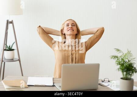 Donna con pausa di lavoro, tenendo braccia dietro la testa Foto Stock