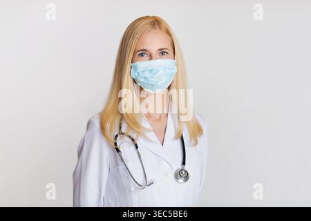 Operatore sanitario che indossa una maschera e un camice da laboratorio in un ambiente clinico Foto Stock