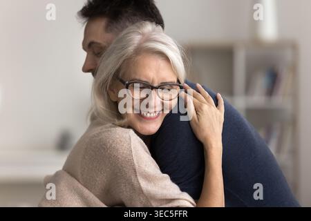 Mamma più grande che coccola strettamente il suo giovane figlio adulto Foto Stock