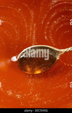 Cucchiaio pieno di sciroppo d'acero dorato. Foto Stock