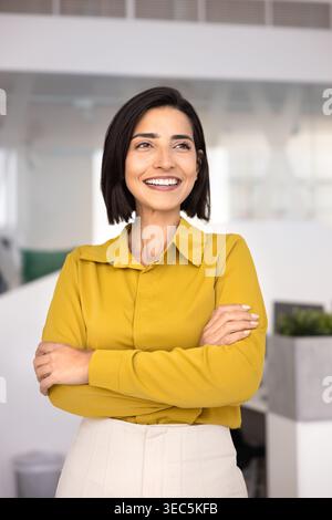 Donna d'affari fiduciosa in piedi in ufficio con le braccia incrociate Foto Stock