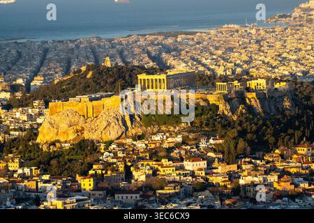 L'Acropoli di Atene si illumina di luce dorata dell'alba, con la città di Atene, il Golfo Saronico e le navi all'orizzonte. Foto Stock