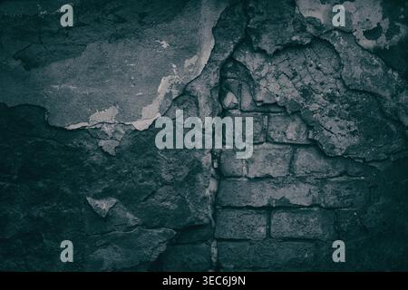 Vecchio muro di mattoni neri con incrinature cadute dall'intonaco. Struttura in mattoni ruvida invecchiata sbriciolata. Sinistro sfondo di Halloween Foto Stock