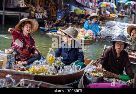 I venditori di donne vendono cibo, fiori e souvenir da barche di legno al mercato galleggiante di Damnoen Saduak a Ratchaburi, Thailandia Foto Stock
