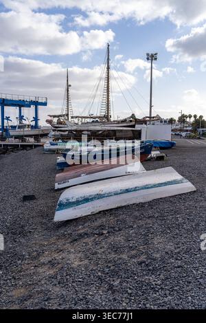L'immagine cattura una tranquilla scena costiera a Lanzarote, con diverse barche che riposano sulla riva sotto un cielo nuvoloso. Foto Stock