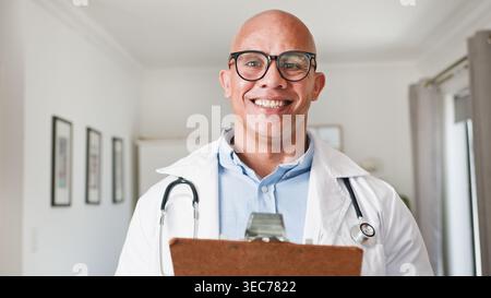 Medico maschio sorridente con stetoscopio e appunti in luminoso moderno Ufficio medico Ritratto Foto Stock