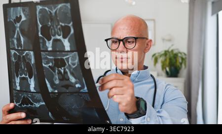 Medico che esamina la pellicola di scansione TC in clinica lettura di immagini a raggi X per la diagnosi medica e la cura del paziente Foto Stock