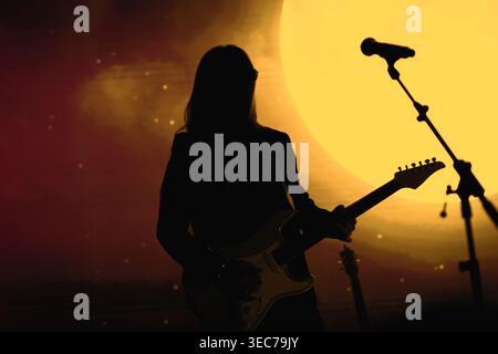 Un artista musicale si erge su uno sfondo lunare luminoso con un supporto per microfono sul palco. Foto Stock