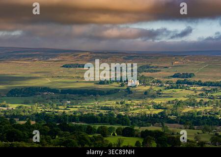 Vista mozzafiato su Wensleydale verso il castello di Bolton sotto i cieli tempestosi e la luce soffusa sui campi verdi Foto Stock