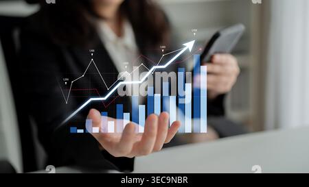 Un professionista aziendale esamina le tendenze dei dati utilizzando grafici digitali e grafici visualizzati in una mano, mettendo in evidenza strategie di crescita e tecnologia in un m Foto Stock