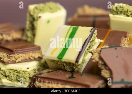 Una vista ravvicinata dei dessert assortiti al pistacchio con strati di cioccolato e colori vivaci. Le prelibatezze sono ben organizzate e ne mostrano le caratteristiche Foto Stock