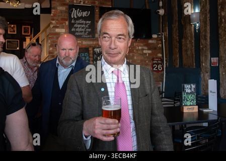 Il leader Reform UK Nigel Farage ha una birra con la gente del posto all'interno di un pub di Halstead, Essex, durante una giornata di campagna intorno all'essex. Credito: Will Colebourne Foto Stock